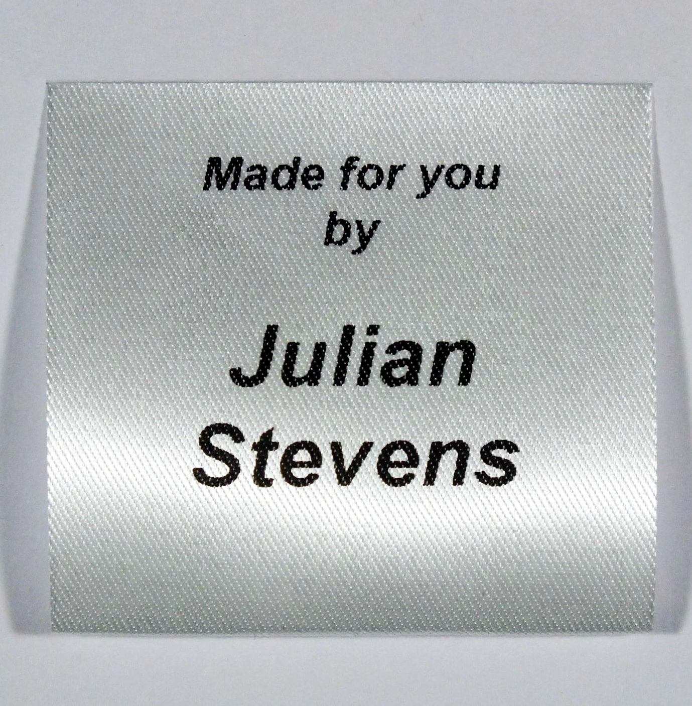 A sew in personalised clothing label printed in Black on Silvery White material