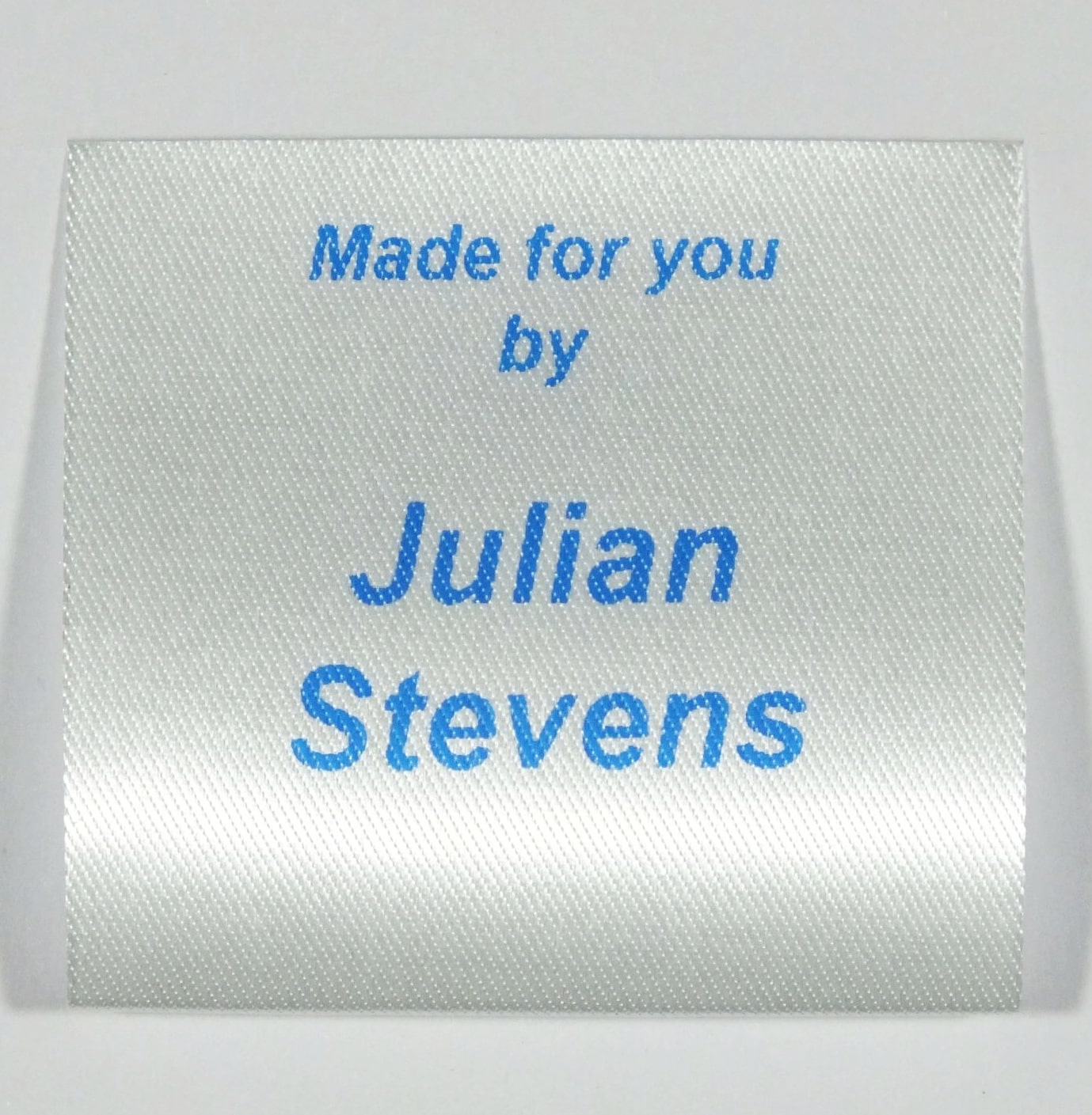 A sew in personalised clothing label printed in Blue on Silvery White material