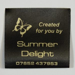 Black sew-in label with Butterfly motif printed in gold.