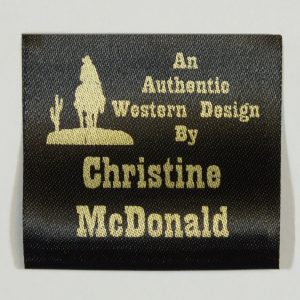 Sew In costume label in black material with gold printed cowboy logo.
